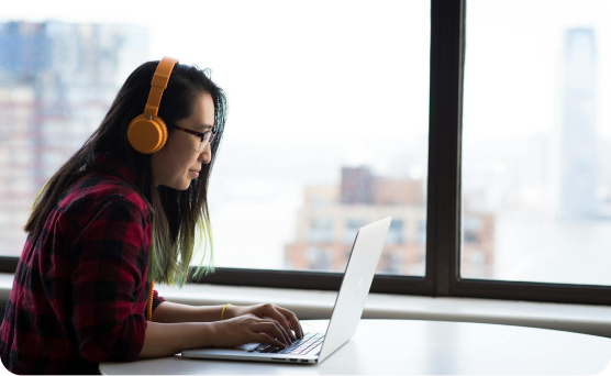 A woman staring at her laptop with headphones on, like shes speaking to clients on a call